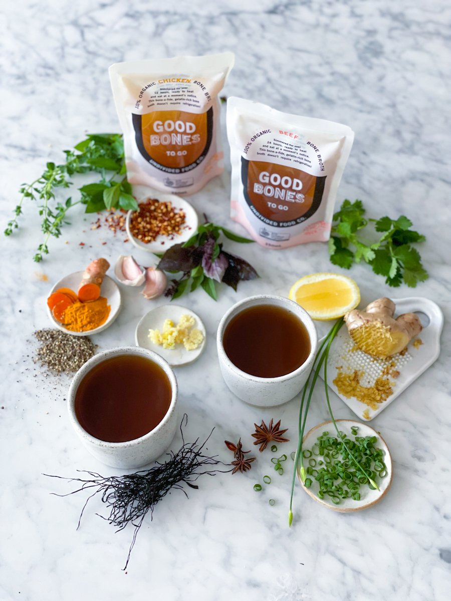 GOOD BONES broth pouches surrounded by cups of broth, herbs and spices